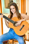 Высокая телка позирует с голыми сиськами с гитарой в руках